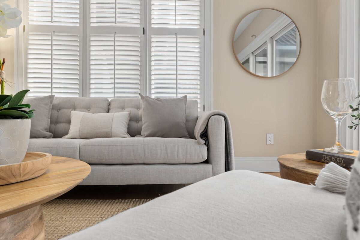 Bright and cozy living room with modern decor, featuring a light grey sofa and a round wall mirror.