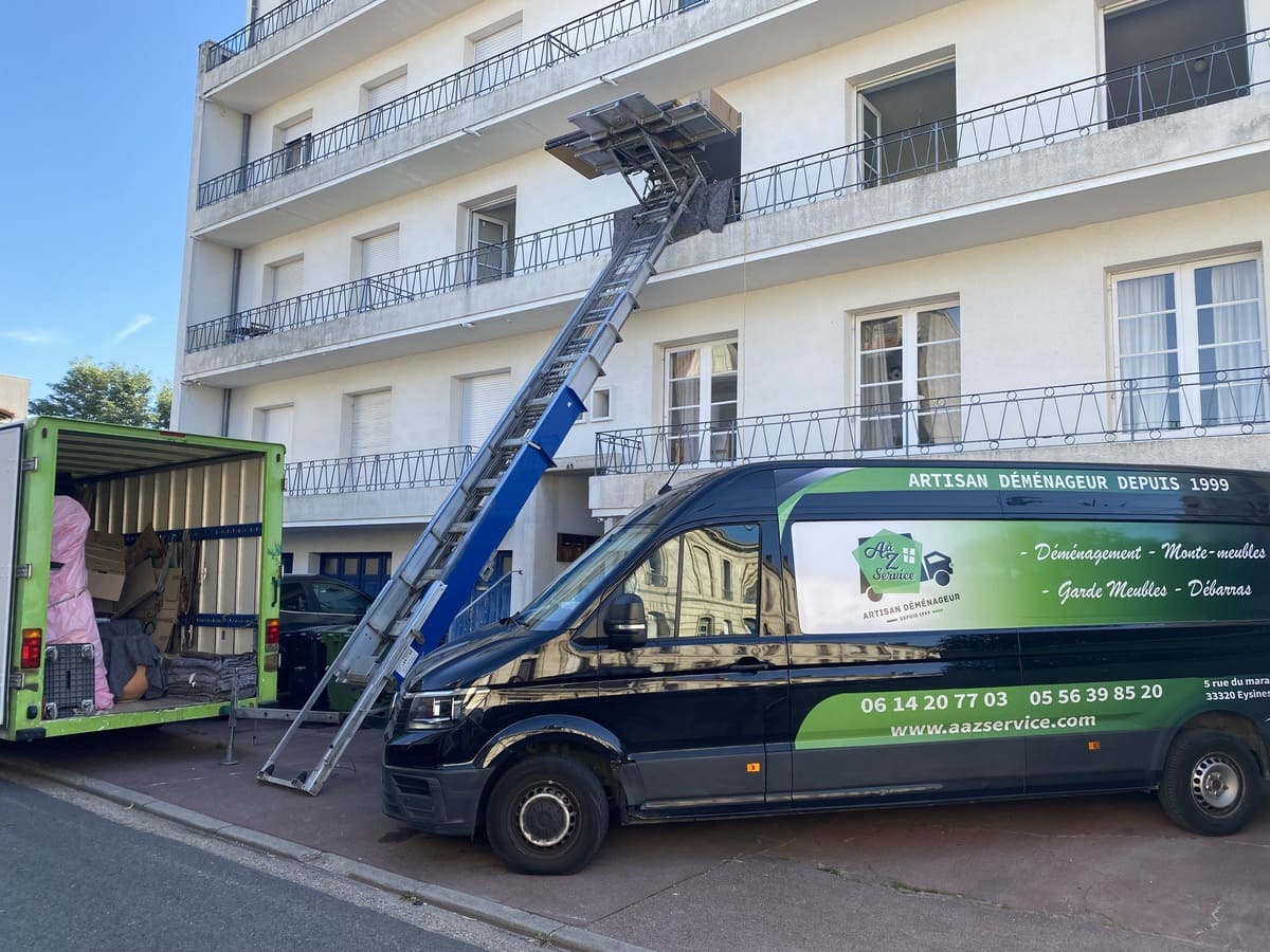 Camion de déménagement et monte-charge devant un immeuble blanc