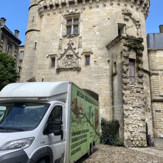 Camion de déménagement placé devant l'entrée d'un ancien bâtiment